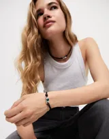 Pulsera de cuero negra, bañada en plata de ley, con un cristal verde central.