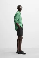 Bermuda negra regular fit confeccionada en tejido de algodón con estructura. Cintura elástica ajustable con cordón, bolsillos laterales y bolsillo trasero de vivo.
