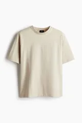 Remera color beige de algodón pesado, corte holgado, cuello redondo ribeteado, hombros caídos y bajo recto.