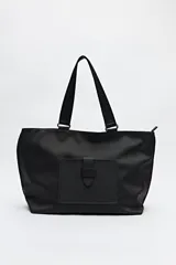 Bolso negro tipo shopper de símil cuero con terminación suave. Tiene asas anchas de cinta y un bolsillo frontal con solapa.