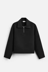 Sudadera negra de corte relaxed fit, con cuello alto y cierre frontal de cremallera metálica.