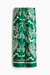 Pantalón de sarga verde con estampado de hojas color crema, tiro alto, cintura elástica con cordón ajustable, corte recto y puño en el bajo.
