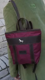 Mochila pequeña color borgoña con detalles en cuero marrón, asa de mano y correas ajustables.