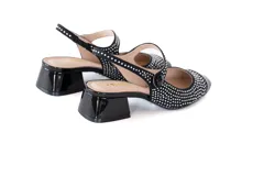 Zapato negro de charol con detalle de puntillas blancas y cierre tipo hebilla.
