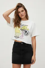 Remera blanca de algodón con estampado de texto y gráficos alusivos a la playa. Corte crop y cuello redondo.