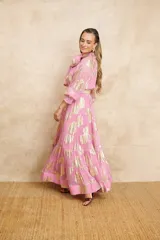 Vestido largo color rosa con estampado dorado, cuello con lazo y mangas largas.