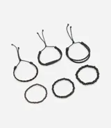 Kit de seis pulseras negras de estilo casual, compuesto por tres pulseras trenzadas con ajuste deslizante y tres pulseras de cuentas elásticas, algunas con detalles cilíndricos.