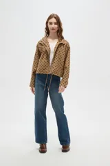 Campera color camel con estampado de lunares negros, cuello alto y cierre frontal. Tiene mangas largas y cordón ajustable en el dobladillo.