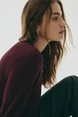 Sweater de punto fino color bordó, con cuello polo y tapeta de botones. Presenta hombros ligeramente caídos y remates acanalados en puños y bajo.