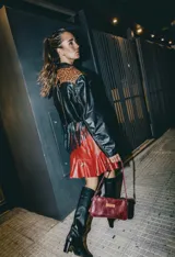 Cartera mini de cuero color bordó, con correa de mano y bolsillo interior con cierre.