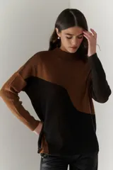 Buzo de punto con diseño geométrico en bloques de color gris y negro, de cuello redondo y mangas largas.