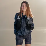 Campera cortaviento gris con estampado camuflado, cierre frontal completo, capucha ajustable y logo de la marca en el pecho.