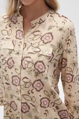 Camisa de viscosa con estampado floral en tonos azul, beige y blanco. Tiene cuello mao, mangas largas y bolsillos en el pecho.