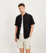 Camisa de hombre de manga corta confeccionada en una mezcla de lino y algodón, marca Marfinno. Presenta un calce confort, cuello clásico, cierre frontal con botones y un bolsillo de parche con solapa en el pecho. Las mangas cuentan con un detalle de dobladillo.