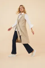 Chaleco largo color beige de lana fina sin teñir, con bolsillos ojal y lazo en la delantera.