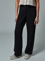 Pantalón negro de vestir, de corte recto y tiro alto, con pinzas en la cintura y bolsillos laterales.