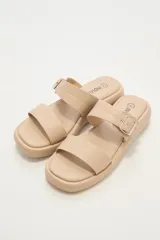 Sandalias bajas color beige con doble tira y hebilla metálica.