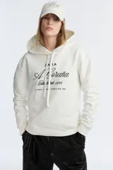 Sudadera marrón con capucha ajustable con cordones y bordado blanco con el texto 'ZAFA A Coruña Established 1975 Rúa Juan Flórez 64-66'.