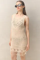 Vestido corto de crochet color crudo, sin mangas y con flecos en el ruedo.