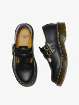 Zapato Mary Jane Dr. Martens modelo 8065, color negro, con doble correa con hebillas doradas, detalles brogue en la puntera y suela con costuras amarillas.