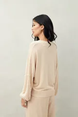 Sweater color beige con cuello redondo y mangas largas. Decorado con perlas sintéticas en forma de rombos.
