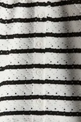 Saco corto blanco con rayas horizontales negras y textura pointelle, de ajuste entallado, cuello redondo y cierre frontal con botones.