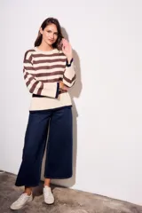 Sweater de punto a rayas horizontales negras y crudas, con cuello redondo y mangas largas. Tiene ribete marrón en puños y ruedo.