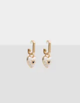 Aros argolla dorados con dije de corazón esmaltado en blanco, con un strass negro central y detalles de rayos en dorado.