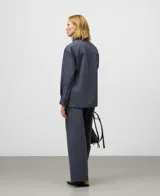 Pantalón de mujer color gris azulado, de corte recto y pierna ancha, tiro medio/alto, con trabillas para cinturón y bolsillos laterales y de vivo en la espalda.