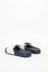 Ojotas tipo slide de color azul marino con tira ancha blanca que lleva el logo de Levi's en rojo.