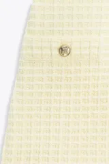Vestido corto color crema confeccionado en tejido elástico con textura. Tiene escote redondo, tirantes anchos y falsos bolsillos de vivo con botón dorado en el delantero.