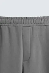 Pantalón jogger negro de corte ancho, confeccionado en tejido de algodón con interior de rizo. Cuenta con cintura elástica ajustable con cordón interior, bolsillos laterales y bolsillo trasero de parche.