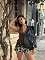 Chaleco marrón de cuero sintético con cuello solapa, cierre frontal asimétrico con cremallera, bolsillos con cremallera y corte ajustado.