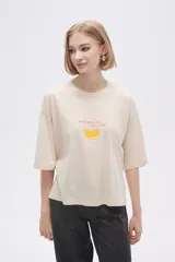 Remera color crema con estampado de limón y texto en color naranja.