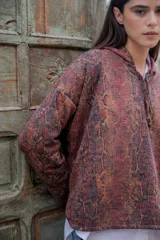 Buzo hoodie con estampado de piel de serpiente en tonos marrones y negros, con capucha forrada en color borgoña y cordón ajustable.