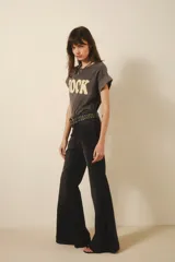 Pantalón jean negro de tiro medio y calce ajustado hasta la rodilla, con pierna acampanada y ruedo ancho.