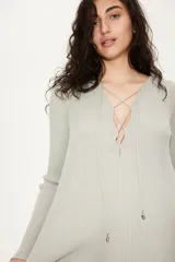 Blusa larga color verde claro en punto acanalado, con escote en V profundo y tiras para atar con cuentas en los extremos.