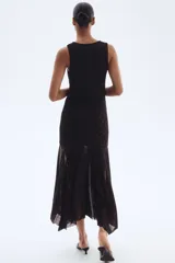 Vestido largo hasta el tobillo, sin mangas, en malla con estampado de leopardo en tonos oscuros. Presenta un escote drapeado tipo cascada, frunces laterales y una falda acampanada con bajo asimétrico y deshilachado.