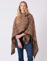 Ruana tejida de la marca Jones New York, con estampado a cuadros en tonos marrón, beige y blanco. Presenta cuello alto y cierre frontal con botón trenca y botón a presión interno. Los bordes están ribeteados en negro.
