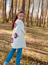 Maxi cardigan color crema de lana merino con bordado de flores rojas y azules.