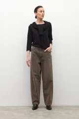 Remera negra de manga tres cuartos con escote bote y un lazo o bufanda del mismo material anudado al cuello.