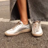 Zapatillas deportivas plateadas con cordones color beige y suela marrón.