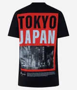 Remera negra alargada de algodón, con cuello redondo y mangas cortas. Estampa en la espalda con la palabra "TOKYO" en rojo y "JAPAN" en celeste, sobre una fotografía en blanco y negro de una calle de Tokio.