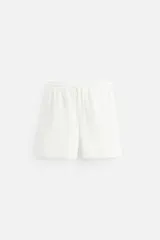 Bermuda blanca de algodón con textura, corte regular fit, cintura elástica ajustable con cordón, bolsillos laterales y bolsillo trasero de vivo.