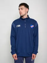 Buzo azul de felpa con medio cierre, cuello alto y mangas largas. Presenta el escudo del Club Nacional de Football en el pecho y el logo de Umbro en la manga.