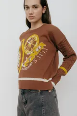 Buzo azul marino tejido en jacquard con diseño de frutas y verduras. Tiene mangas tejidas en ochos, bordado en la espalda y puños con agujerito para el dedo.