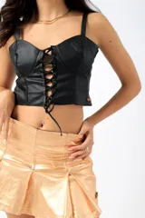 Corset plateado de cuero sintético con tirantes finos y ajuste frontal con cordones.