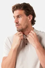 Remera de manga corta color azul grisáceo con cuello mao y tapeta de botones. Los puños de las mangas y el cuello son de color azul marino contrastante. Presenta un pequeño logo bordado en el pecho.