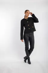 Chaqueta negra con textura, cuello redondo, cierre frontal con botones dorados y bolsillos delanteros con solapa y botón dorado.
