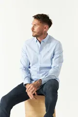 Camisa celeste a rayas verticales blancas, de corte slim fit, con cuello abotonado y logo bordado en el pecho.